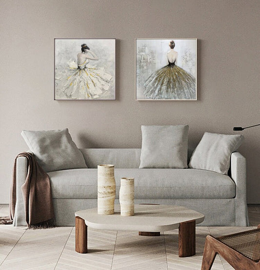 May include: Two framed paintings of women in flowing dresses. The paintings are in a living room setting with a couch, coffee table, and decorative vases.