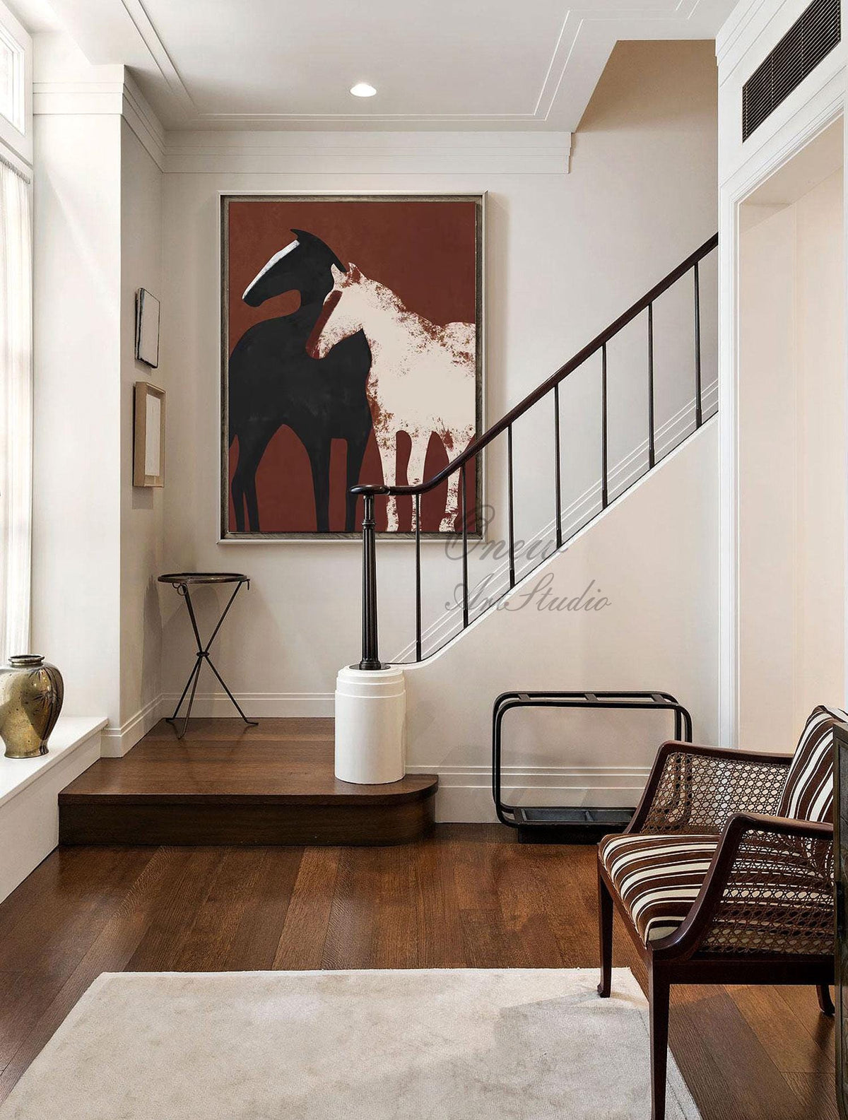 May include: Abstract painting of two horses, one black and one white, on a red background. The painting is hanging on a wall in a hallway with a staircase.