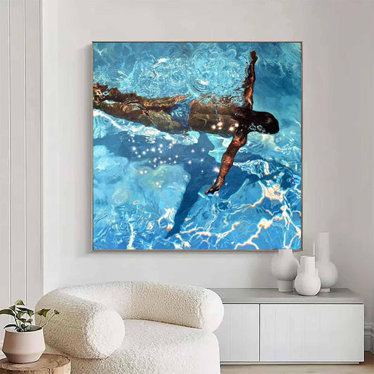 May include: A square canvas art print depicts a person swimming underwater in a pool. The water is a vibrant blue with light reflections. The person is dark-skinned with their arm extended upwards. The artwork is framed in a gold-colored frame.