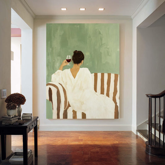 May include: An abstract painting depicts a person in a white dress seated on a striped sofa, holding a glass of red wine. The background is a muted green, creating a serene atmosphere. The artwork is displayed in a well-lit hallway.