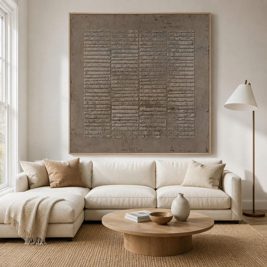 May include: A large square wall art piece featuring a textured, taupe-colored surface with a grid of horizontal, raised rectangular segments. The artwork is framed in a light-toned wood and displays a weathered, earthy finish with subtle variations.