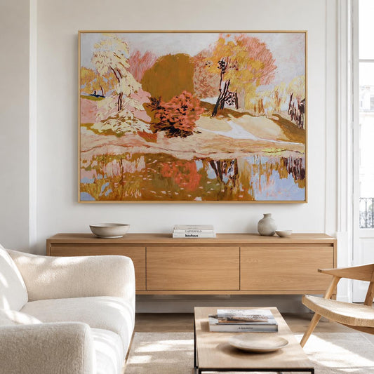 May include: A large rectangular landscape painting in a light wood frame featuring an impressionistic scene of trees in shades of orange, yellow, and pink reflected in a body of water, displayed on a wall above a long wooden media console.