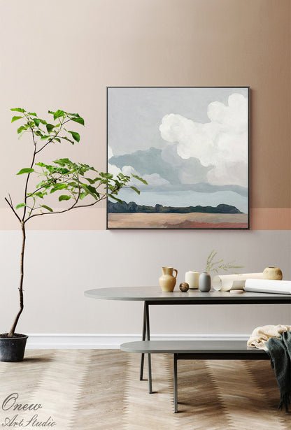 May include: A framed landscape painting depicts a cloudy sky over a distant land. The artwork is displayed in a modern interior with a round table, decorative vases, and a small potted tree. The color palette includes muted blues, browns, and grays.