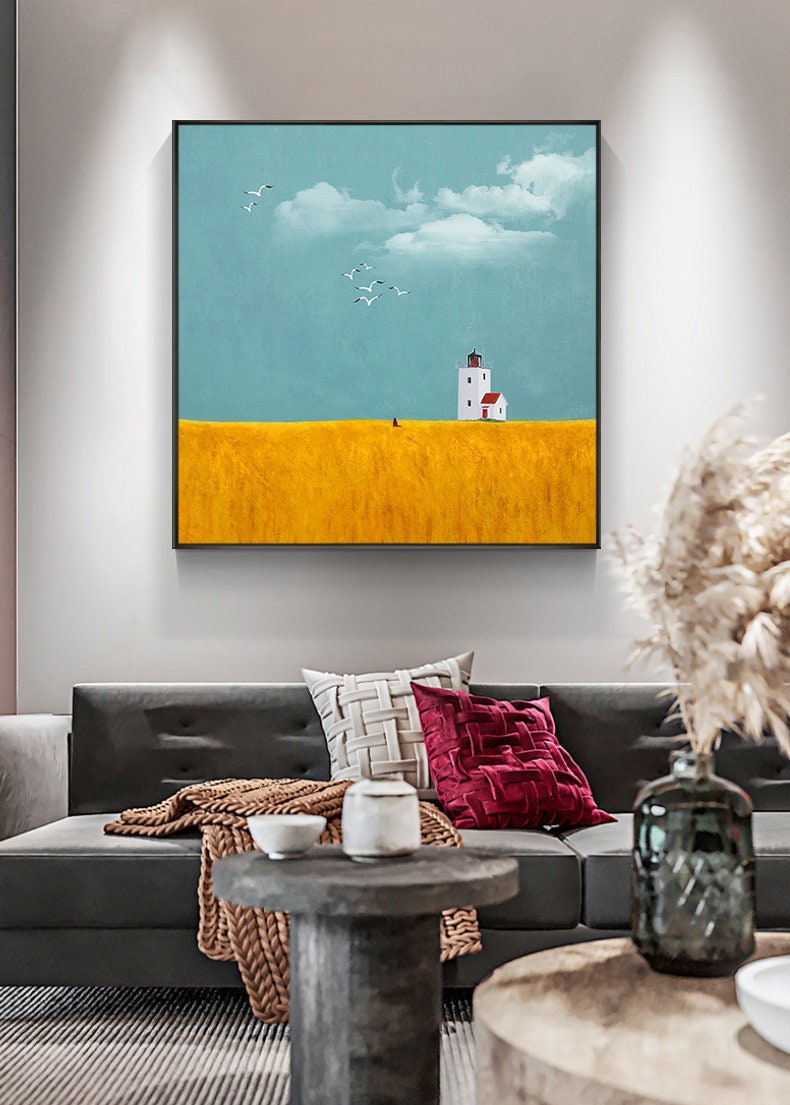 May include: A painting of a white lighthouse with a red roof on a yellow field. The sky is blue with white clouds and there are birds flying in the sky.