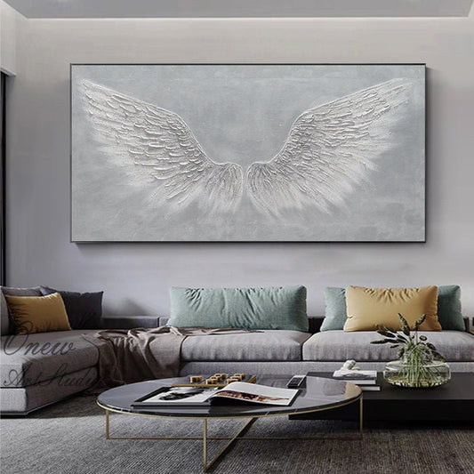 May include: A large abstract painting of white angel wings on a gray background. The wings are textured and appear to be made of feathers. The painting is hanging on a wall in a living room setting.
