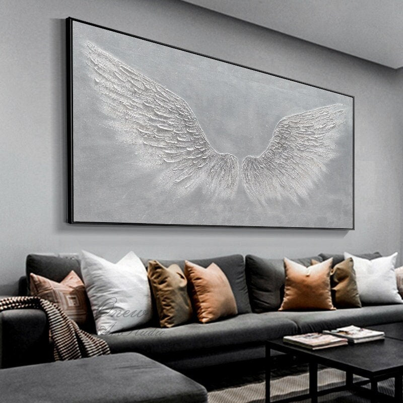 May include: A large, rectangular canvas painting with a gray background and white textured angel wings. The wings are painted in a realistic style and have a 3D effect.