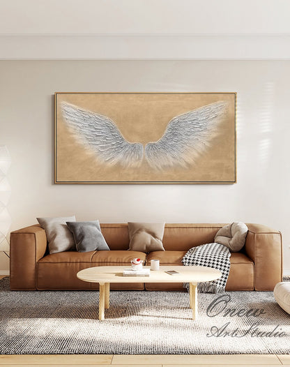 May include: A large abstract painting of white angel wings on a beige background. The painting is framed and hanging on a wall in a living room.