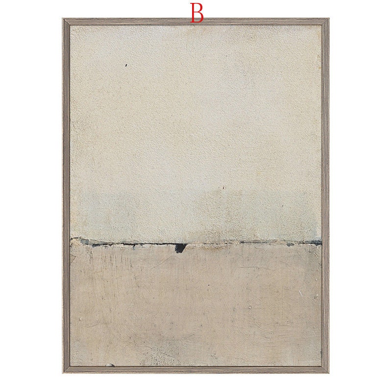 May include: Abstract art print in a light beige and gray color scheme. The print features a horizontal line dividing the canvas into two sections. The top section is a lighter beige, while the bottom section is a darker gray. The print is framed in a light wood frame.