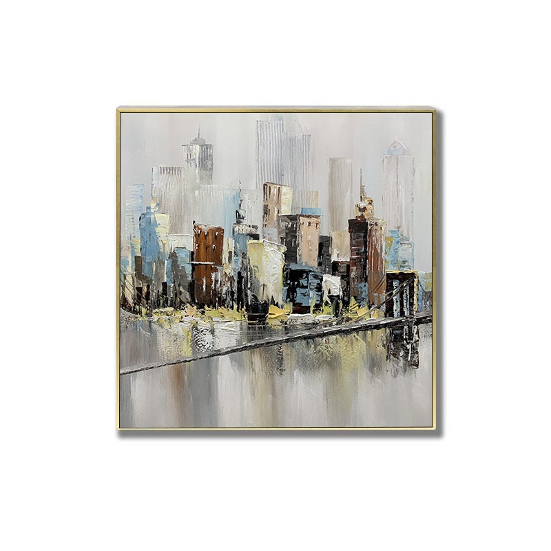 May include: Abstract painting of a cityscape with buildings in shades of brown, blue, and gray. The buildings are reflected in a body of water in the foreground. The painting has a gold frame.