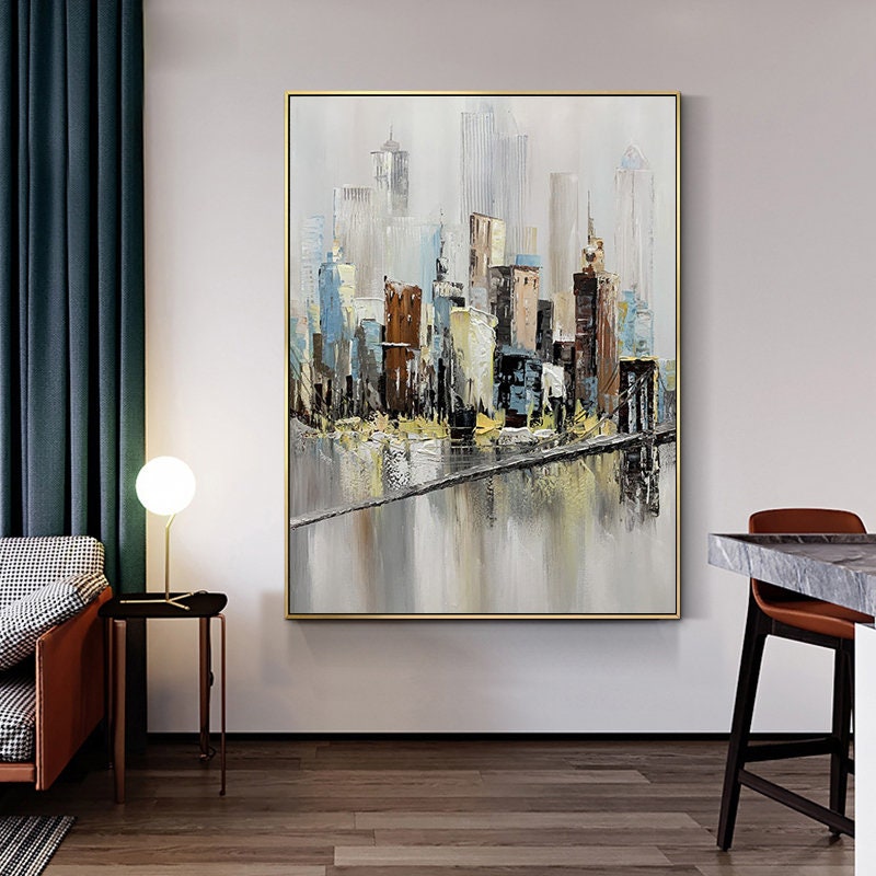 May include: Abstract painting of a cityscape with a bridge and water reflection. The painting is done in shades of gray, brown, blue, and yellow. The painting is framed in gold.