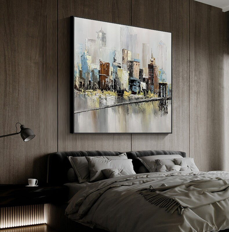 May include: Abstract painting of a cityscape with a river in the foreground. The painting is done in shades of gray, blue, brown, and yellow. The buildings are stylized and the river is reflective.