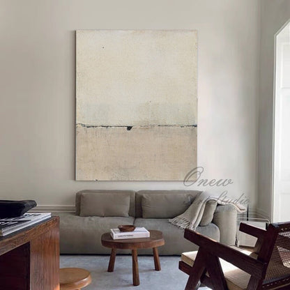 May include: Abstract painting with a horizontal line dividing the canvas into two sections. The top section is a light beige color, while the bottom section is a slightly darker beige. The painting is hanging on a white wall in a living room setting.