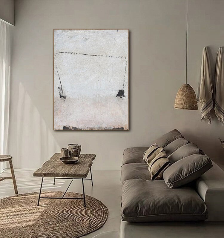 May include: Abstract painting with black lines and shapes on a white background. The painting is hanging on a wall in a living room setting with a couch and a coffee table.