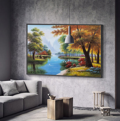May include: A framed painting of a landscape with a river, trees, and a blue sky. The trees are in shades of green, yellow, and orange. The river is blue and reflects the sky. There are white birds swimming in the river.