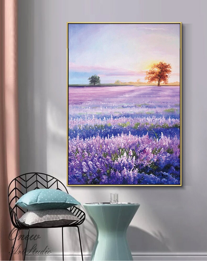 May include: A painting of a lavender field with a sunset in the background. The field is filled with purple flowers and there are two trees in the distance. The sky is a soft pink and orange.