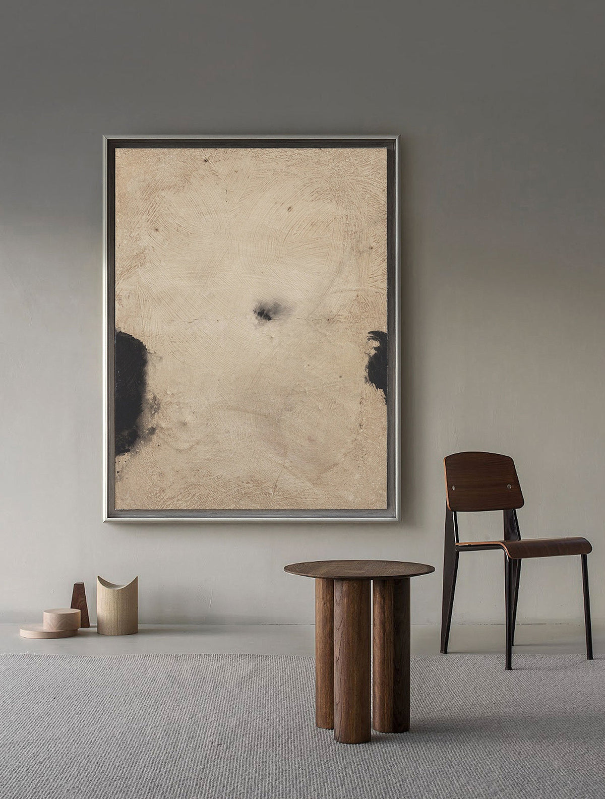 May include: A brown wooden table with a round top and four legs. The table is in a room with a framed abstract painting on the wall and a wooden chair with a black metal frame.
