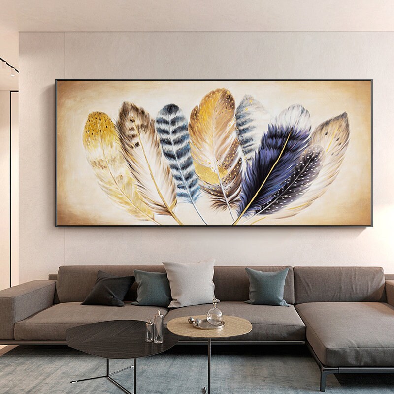 May include: A painting of a group of colorful feathers in shades of gold, brown, blue, and white. The feathers are arranged in a fan shape and are set against a light beige background.
