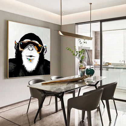 May include: A black and white painting of a monkey wearing sunglasses and a colorful beaded necklace. The painting is hanging on a wall in a dining room with a marble table and black chairs.