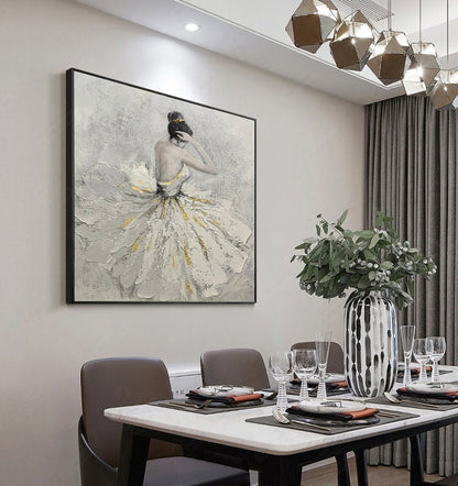 May include: A framed painting of a woman in a white dress with gold accents. The woman is standing with her head tilted down and her hands on her hair. The painting is on a white wall in a dining room setting.