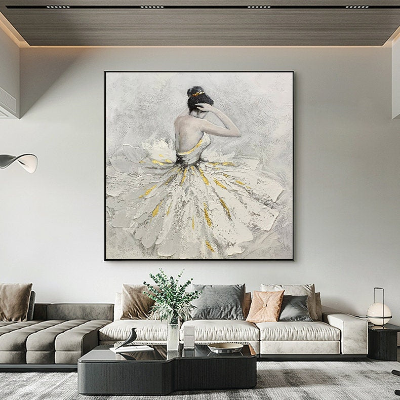 May include: A painting of a ballerina in a white tutu with gold accents. The ballerina is facing away from the viewer and has her hair pulled back in a bun. The background is a light gray.