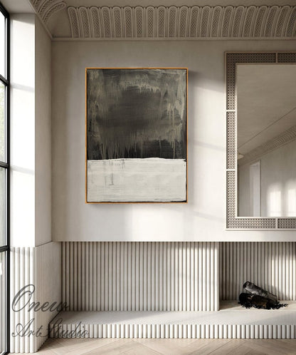 May include: Abstract painting with a dark gray and white color scheme. The painting is framed in a thin, gold frame and is hanging on a white wall in a modern interior.
