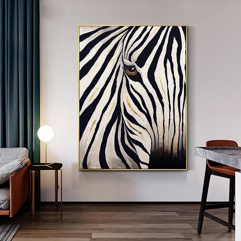May include: A framed canvas art print featuring a close-up of a zebra's face. The artwork showcases bold black and white stripes with gold accents, and a detailed brown eye. The painting is set against a neutral background, creating a striking contrast.
