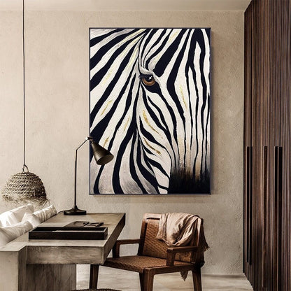 May include: A black and white zebra painting with gold accents. The artwork features a close-up of the zebra's face, with its eye visible. The painting is framed and hangs on a neutral-colored wall, adding a touch of wildlife to the room.