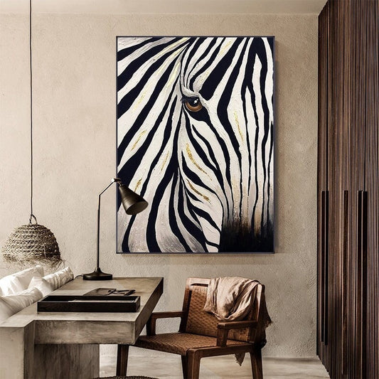 May include: A black and white zebra painting with gold accents. The artwork features a close-up of the zebra's face, with its eye visible. The painting is framed and hangs on a neutral-colored wall, adding a touch of wildlife to the room.