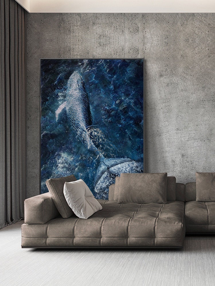 May include: A large, abstract painting of a whale breaching in a blue and white ocean. The painting is hanging on a wall above a brown sectional sofa.