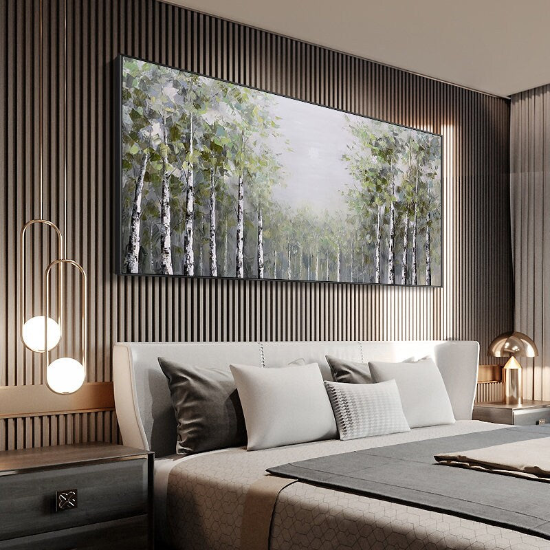 May include: A large, rectangular canvas painting depicting a forest scene with a muted color palette. The painting features a group of birch trees with white bark and green leaves, set against a hazy background. The painting is framed in black and hangs on a wall with vertical wood paneling.