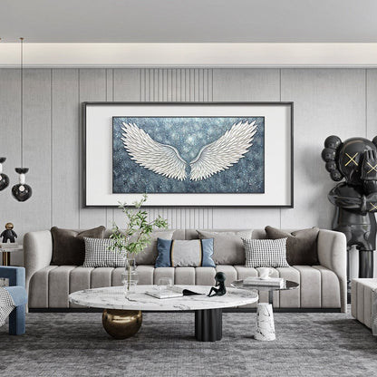 May include: A living room interior with a gray sofa, a white marble coffee table, and a large framed painting of white angel wings against a blue starry background.