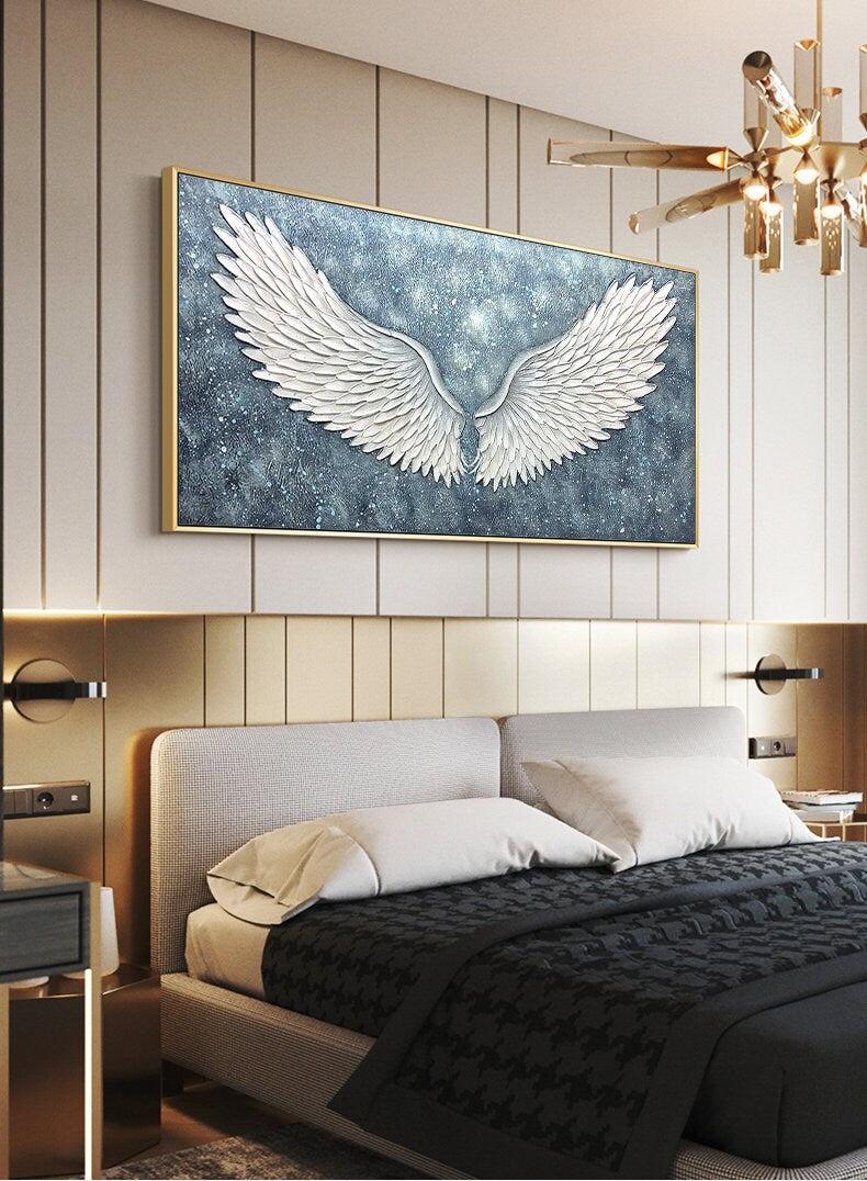 May include: A large canvas painting with a gold frame depicting a pair of white angel wings against a blue and white starry background.