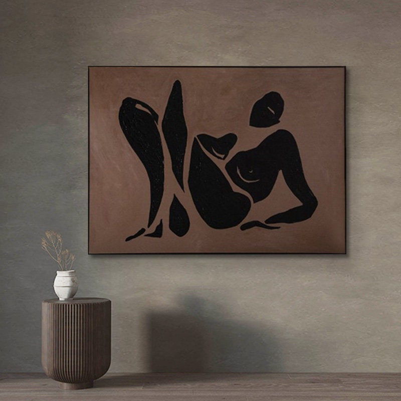 May include: Abstract art print featuring a black silhouette of a person in a reclining pose on a brown background.