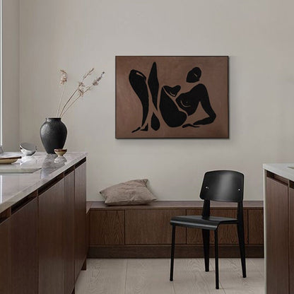 May include: A black and white abstract art print of a person in a reclining pose on a brown background. The print is hanging on a wall in a modern kitchen with wooden cabinets and a black chair.