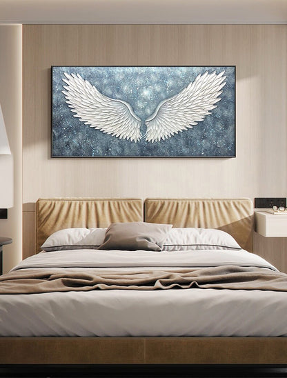 May include: A white canvas painting of a pair of angel wings against a blue and white starry background. The wings are large and detailed, with a 3D effect.
