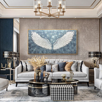 May include: A white, textured, angel wing canvas painting with a blue and white starry background. The painting is hanging on a wall in a living room with a white sofa, a black and white patterned ottoman, and a black coffee table.