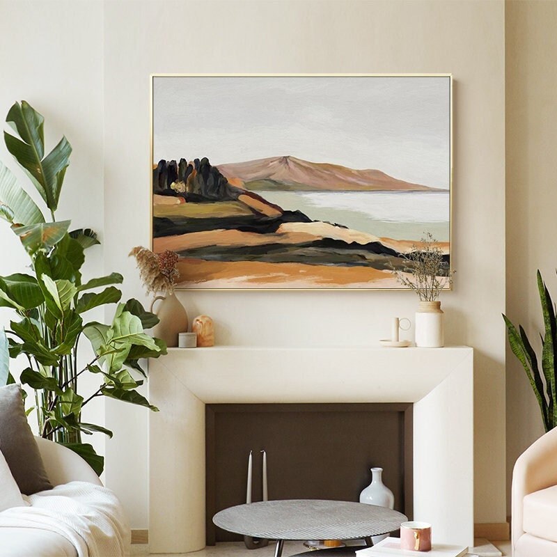May include: Abstract landscape painting with a mountain range, water, and trees in shades of brown, green, and blue. The painting is framed in a gold frame and hangs on a white wall.