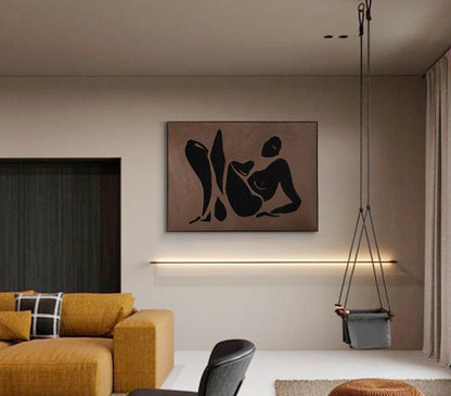 May include: A black and white abstract art print of a person in a reclining pose. The print is on a brown background and is framed in a black frame. The print is hanging on a wall in a living room.
