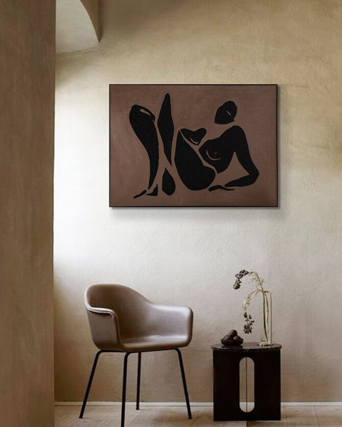 May include: A black and white abstract painting of a person in a reclining pose. The painting is on a brown background and is framed in a black frame.
