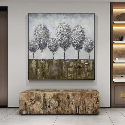 May include: A framed abstract painting of a row of five gray trees with white accents against a light blue background. The trees are set against a brown and gold textured background.