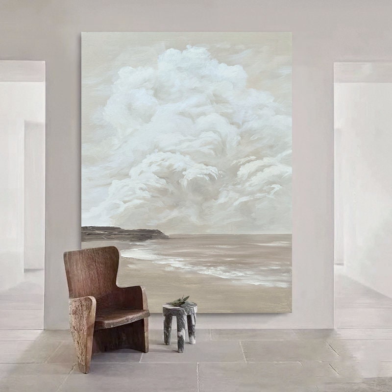 May include: A large abstract painting depicting a seascape with a white cloud formation above a sandy beach and ocean. The painting is in shades of beige, brown, and white.