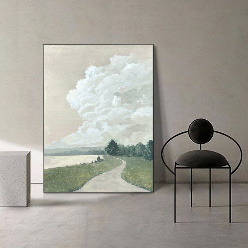 May include: A painting of a landscape with a winding road leading to a forest. The sky is filled with fluffy white clouds. The painting is framed in a black frame.