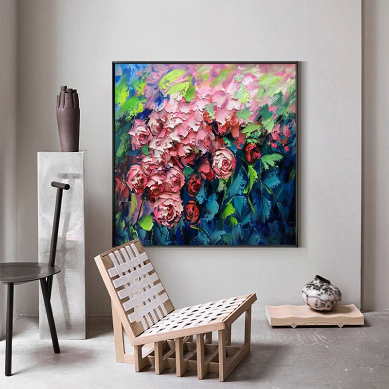 May include: A painting of a bouquet of pink roses with green leaves against a blue background. The painting is framed in black and is hanging on a wall.