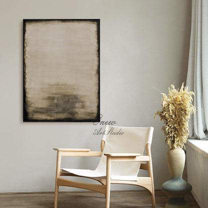 May include: Abstract painting with a black frame, featuring shades of brown and beige. The painting is hanging on a white wall in a room with a wooden chair and a vase with dried flowers.