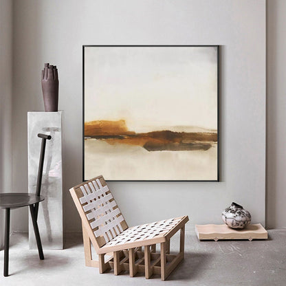May include: Abstract landscape painting with brown and white tones. The painting is framed in black and hangs on a white wall. A wooden chair with a white woven seat sits in front of the painting.