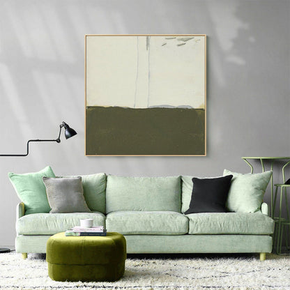 May include: A green velvet ottoman sits in front of a light green sofa with gray and black throw pillows. A framed abstract painting with a white background and a green and brown landscape hangs on the wall above the sofa.