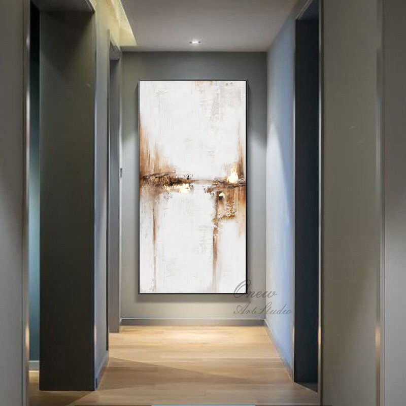 May include: Abstract painting with brown and white hues. The painting is on a canvas and is hanging on a wall in a hallway. The painting has a modern and minimalist style.