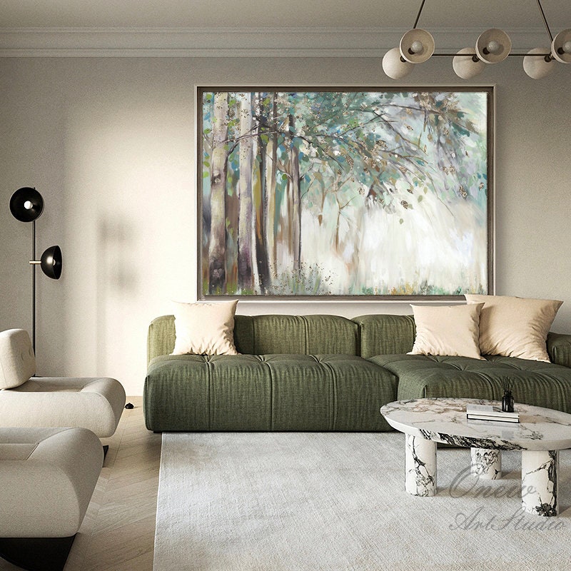 May include: A large abstract painting of a forest scene with trees and foliage in shades of green, brown, and white. The painting is hanging on a wall above a green sofa with beige pillows.