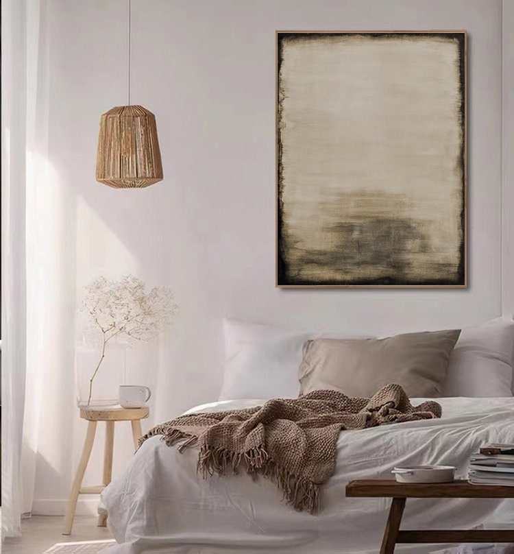 May include: A bedroom interior with a white bed, a brown blanket, and a wooden stool. A large abstract painting in shades of brown and beige hangs on the wall above the bed.