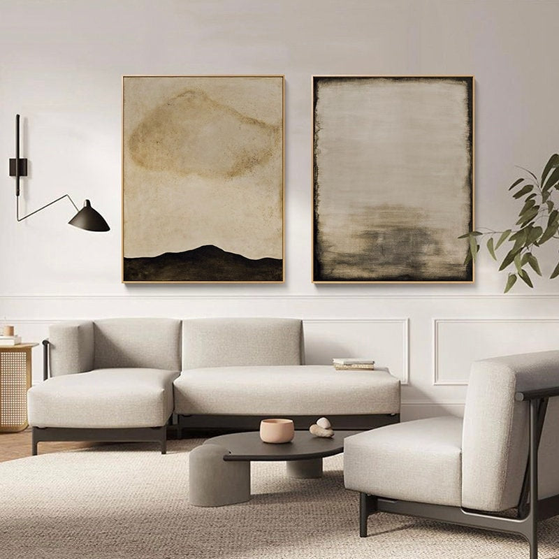 May include: Two abstract paintings in muted tones of brown and beige. The painting on the left features a dark brown mountain range with a light brown cloud shape above. The painting on the right has a light brown background with dark brown horizontal lines.